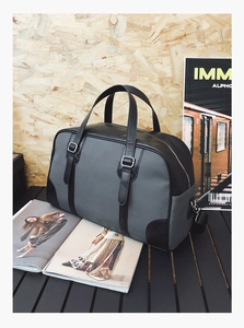 Detailed view of a grey fabric and black leather travel bag on a wooden table