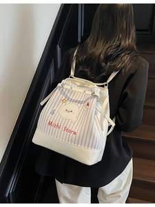 Sac à dos en toile rayée bleue avec imprimé phoque et base en cuir blanc porté par modèle