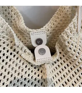 Close-up of the secure magnetic snap closure on a woven straw beach tote bag