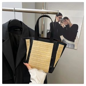 Detail of contrast stitch straw tote bag with black leather trim and woven texture