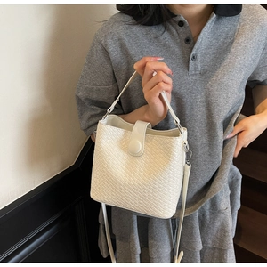 Détail du sac seau tressé blanc avec ferrures argentées et bandoulière réglable