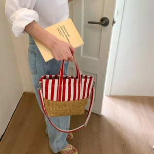 Detail of canvas tote bag featuring red stripes, woven straw base and adjustable straps