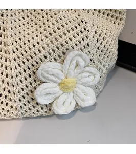 Close-up of woven tote bag with 3D white daisy flower detail and knit mesh texture