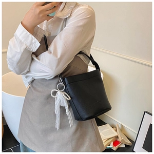 Chic black bucket bag with lychee pattern leather and pearl silk bow on a shoulder model