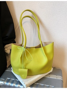 Fluorescent green litchi grain tote bag with small pouch on a silver suitcase