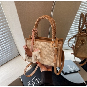 Détail du sac tissé crème avec bordure en cuir marron et breloque pégase blanc