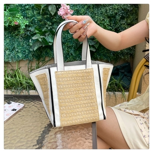 Detailed shot of a woven beach tote bag with white leather panels and black edge trim