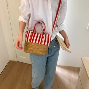 Detail view of red and white striped canvas bag with woven straw bottom panel
