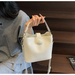 Détail du sac seau tissé blanc avec cuir PU texturé et fermeture à bouton-pression rond