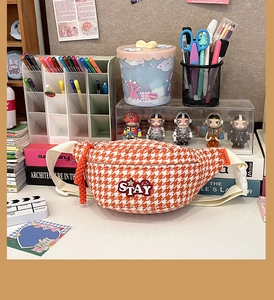 Détail du sac banane à motif pied-de-poule orange avec écusson smiley et cordon