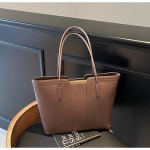 Détail du cuir marron à motif litchi et des coutures de précision sur le sac cabas