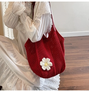 Detail of red crochet tote bag with white 3D flower and mesh design on a model