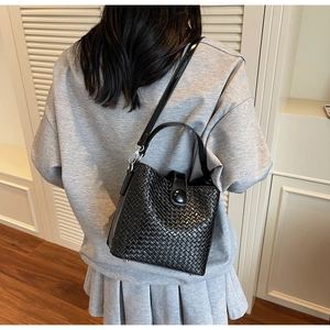 Détail du sac seau noir tressé montrant la texture et la boucle métallique au dos