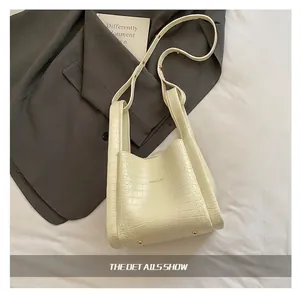 Detail of cream faux crocodile texture shoulder bag with adjustable metal buckle strap