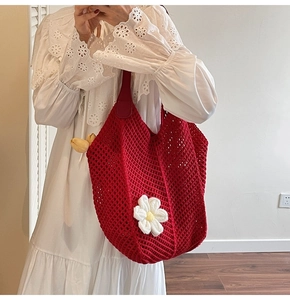 Close-up of a red crochet tote bag with a white flower and soft knitted texture