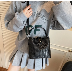 Détail du sac seau noir tressé montrant la texture premium et le fermoir métallique