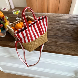 Close-up of red striped canvas and straw tote bag on a rustic wooden table scene