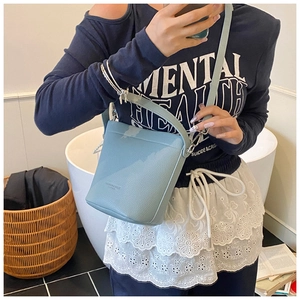 Dettaglio della pelle a grana e della tracolla regolabile di questa borsa a secchiello blu