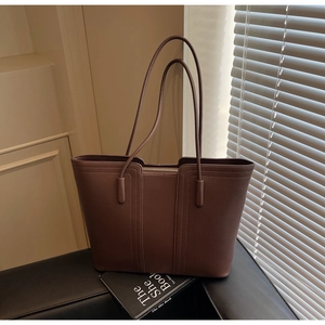 Vue détaillée de la texture du cuir marron foncé et des coutures sur le sac cabas