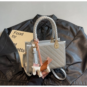 Vue détaillée d'un sac à main argenté tressé avec un charmant pendentif de cheval