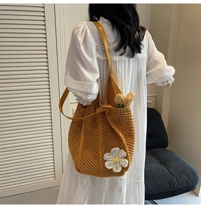 Detail of yellow woven tote bag featuring a large white daisy and leather strap