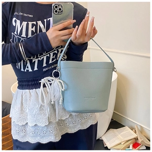 Light blue bucket bag with pebble leather texture and decorative pearl lace tassel