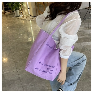 Détail du sac fourre-tout en toile violette avec slogan 'Stay soft' et bandoulière de près