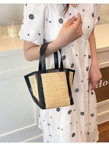 Large woven tote bag with black leather trim and straw texture shown with a model