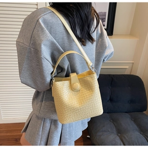 Détail du sac seau tissé jaune clair montrant sa surface texturée et sa bandoulière