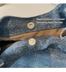 Macro shot of blue denim bag with glitter finish, silver magnetic buckle and pearl strap