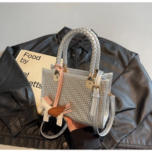 Détail d'un sac à main tissé argenté avec breloque Pégase et bandoulière réglable