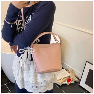 Borsa a secchiello rosa con trama litchi, ciondoli di perle e pizzo con tracolla elegante