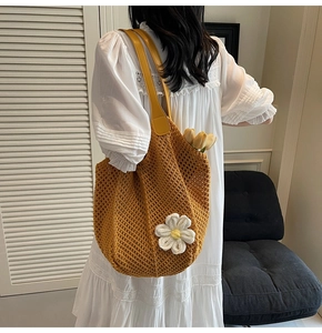 Close-up of yellow woven tote bag featuring 3D white floral patterns and leather straps