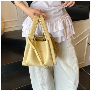 Detail of light yellow crocodile texture handbag with adjustable strap and gold hardware