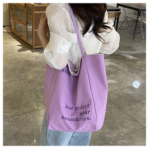 Détail du sac fourre-tout violet en toile avec inscription Stay soft protect boundaries