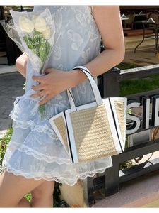 Minimalist straw and white leather woven tote bag held by model in outdoor scene
