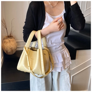 Pale yellow crocodile texture bucket bag shown with dual handles and detachable strap
