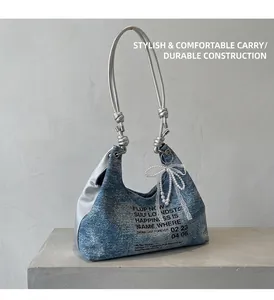 Detail of blue denim shoulder bag with silver knot handle and lace pearl bow charm