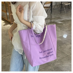 Détail du sac fourre-tout en toile violette avec texte et bandoulière à carreaux jaunes