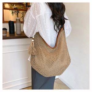 Detail der gewebten Stroh-Hobo-Tasche mit braunem Lederbesatz und Quaste im Cafe