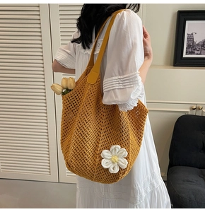 Close-up of yellow knit tote bag featuring a handmade white crochet flower detail