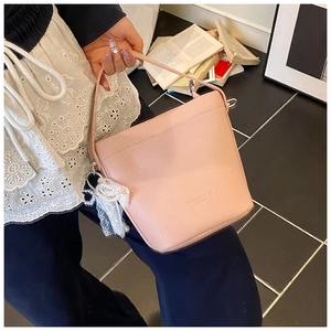 Detailed texture of pink litchi grain leather bucket bag with lace bow and pearl charm
