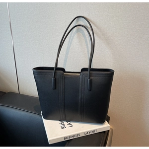Détail d'un sac cabas en cuir noir avec grain de litchi et fermeture éclair métallique robuste
