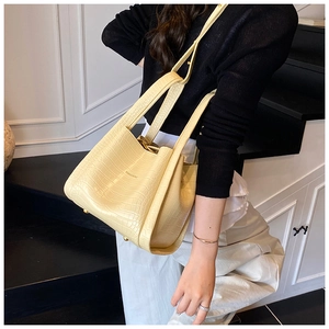 Close-up of minimalist beige crocodile pattern handbag with metal brand logo detail