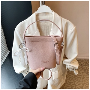Dettaglio borsa a secchiello rosa in pelle martellata con fiocco di pizzo e perle