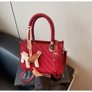 Détail du sac cabas rouge tissé avec un pendentif pégase en cuir et poignée texturée