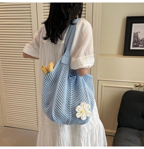 Detail of light blue crochet beach tote with white daisy floral 3D accents and leather strap