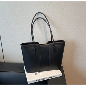 Détail du cabas en cuir grainé noir avec fines bretelles et surpiqûres verticales