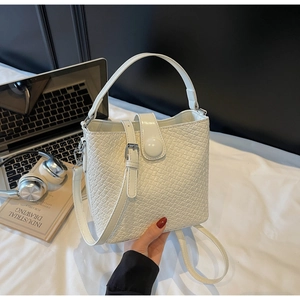 Détail d'un sac seau blanc à motif crocodile avec boucles argentées et bandoulière
