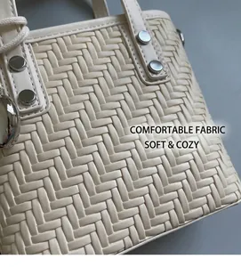 Dettaglio macro della trama intrecciata beige con borchie argentate sulla borsa alla moda